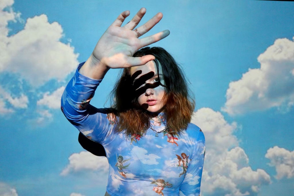 Girl stands in front of wall with sky projection on her for projector photoshoot.